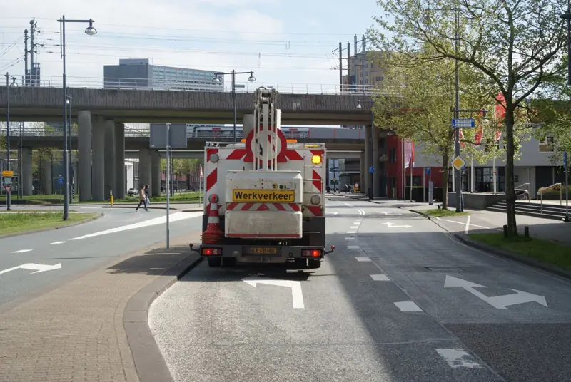 Werkverkeerwagen met pijlbord rijdt over een stadsweg