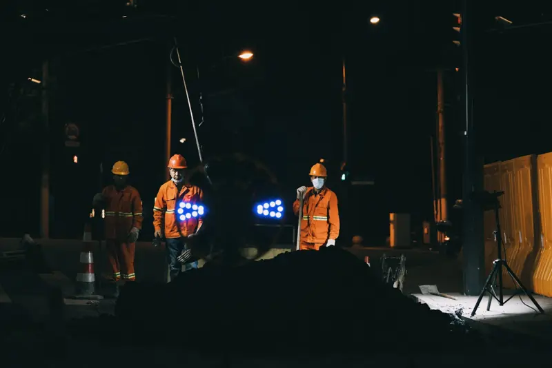 Wegwerkers met verlichting aan het werk in de nacht